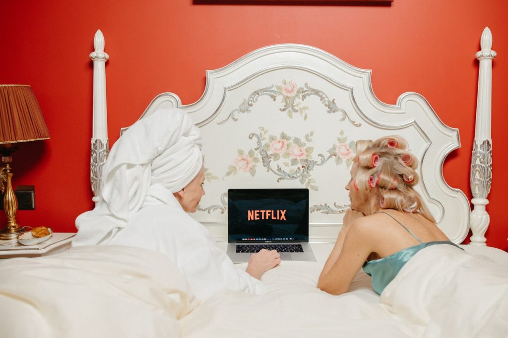 2 women watching netflix on the bed