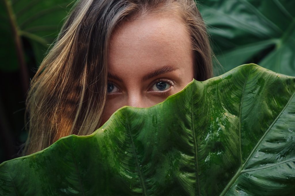 Woman Hiding Beside a Green Leaf
