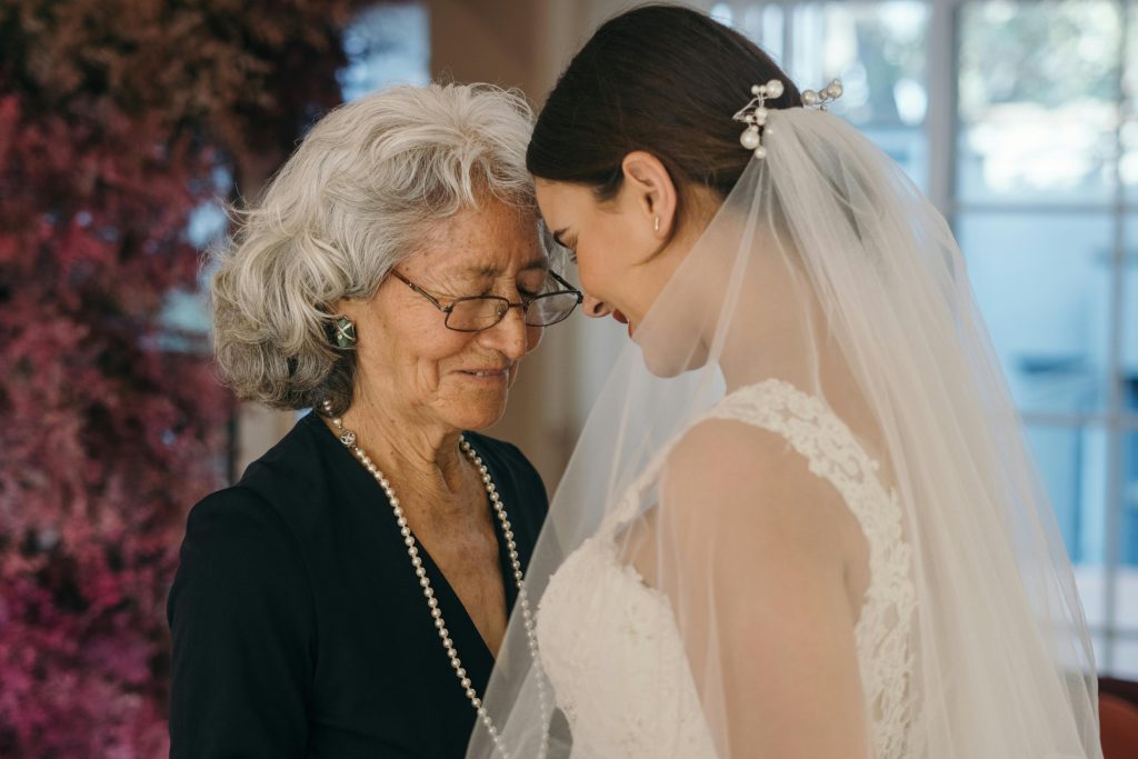 bride and mother of the bride standing forehead to forehead, smiling warmly