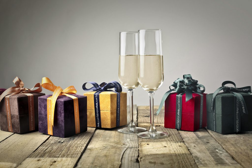 two glasses of champagne placed between gift boxes decorated with ribbons